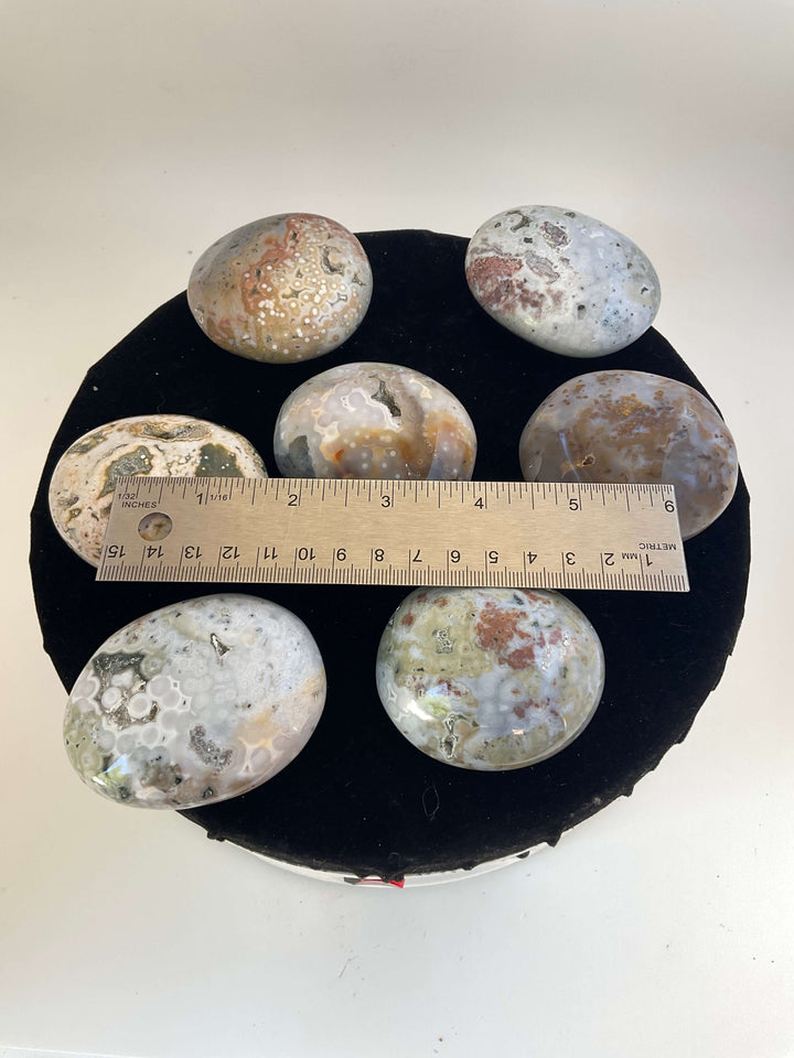 Ocean Jasper Pebble Palmstones displayed on a black background, showcasing its unique natural patterns.