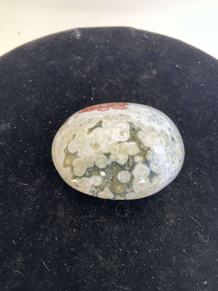 Ocean Jasper Pebble Palmstones displayed on a black background, showcasing its unique natural patterns.