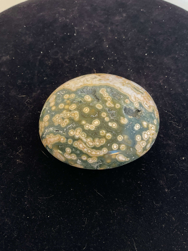 Ocean Jasper Pebble Palmstones displayed on a black background, showcasing its unique natural patterns.