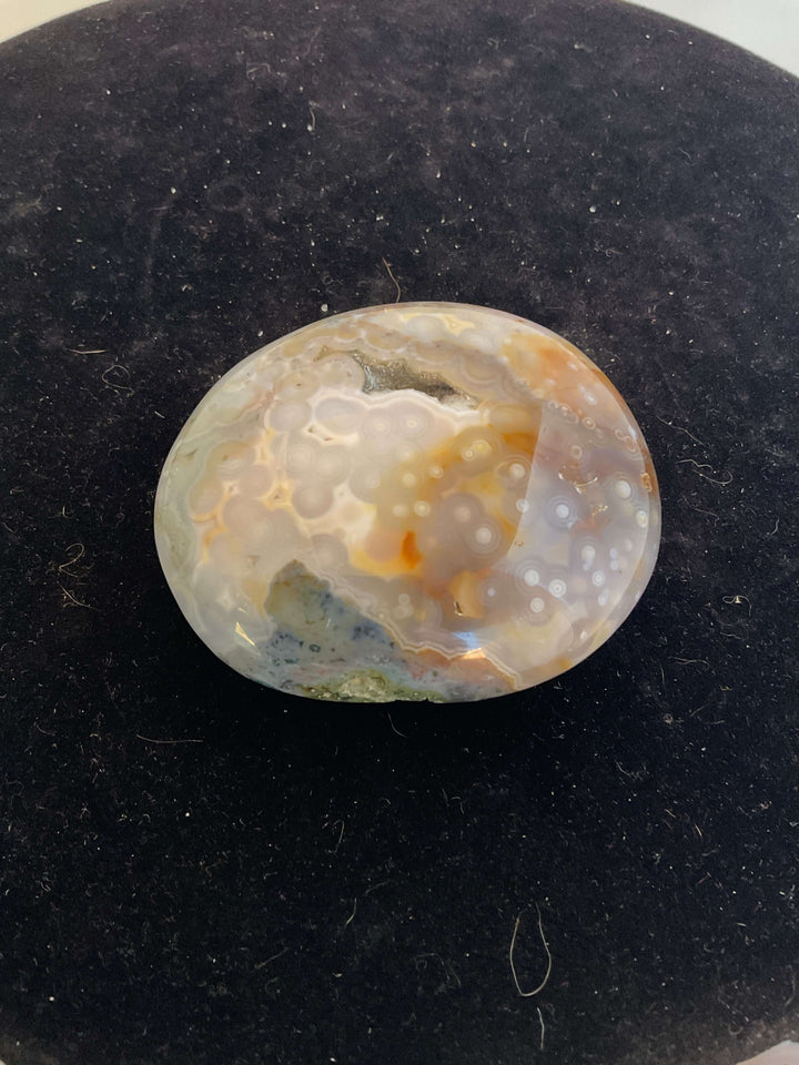 Ocean Jasper Pebble Palmstones displayed on a black background, showcasing its unique natural patterns.