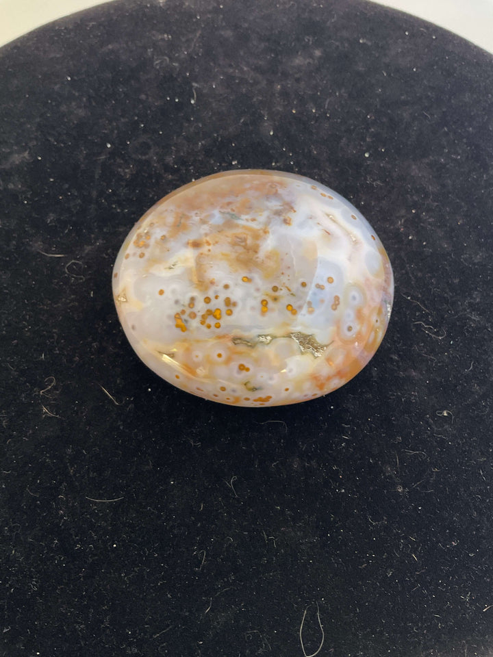 Ocean Jasper Pebble Palmstones displayed on a black background, showcasing its unique natural patterns.