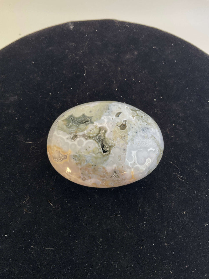 Ocean Jasper Pebble Palmstones displayed on a black background, showcasing its unique natural patterns.