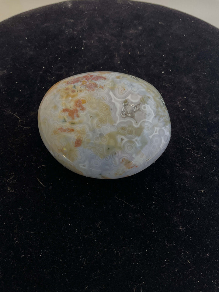 Ocean Jasper Pebble Palmstones displayed on a black background, showcasing its unique natural patterns.