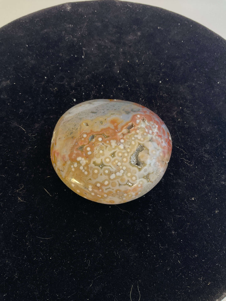 Ocean Jasper Pebble Palmstones displayed on a black background, showcasing its unique natural patterns.