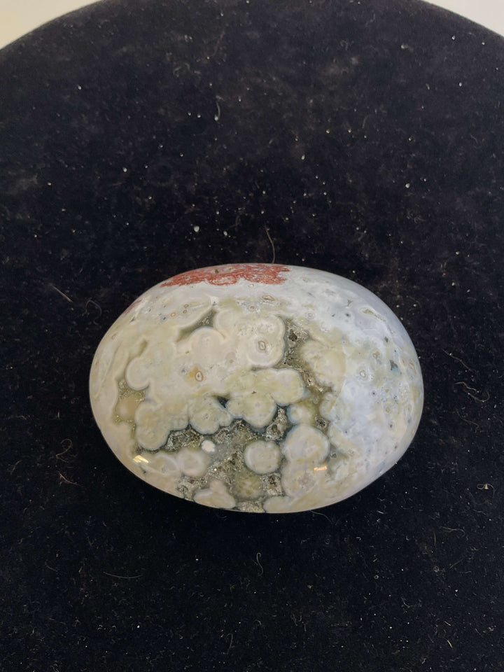 Ocean Jasper Pebble Palmstones displayed on a black background, showcasing its unique natural patterns.