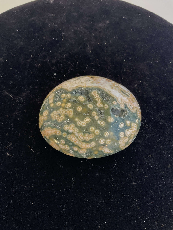 Ocean Jasper Pebble Palmstones displayed on a black background, showcasing its unique natural patterns.