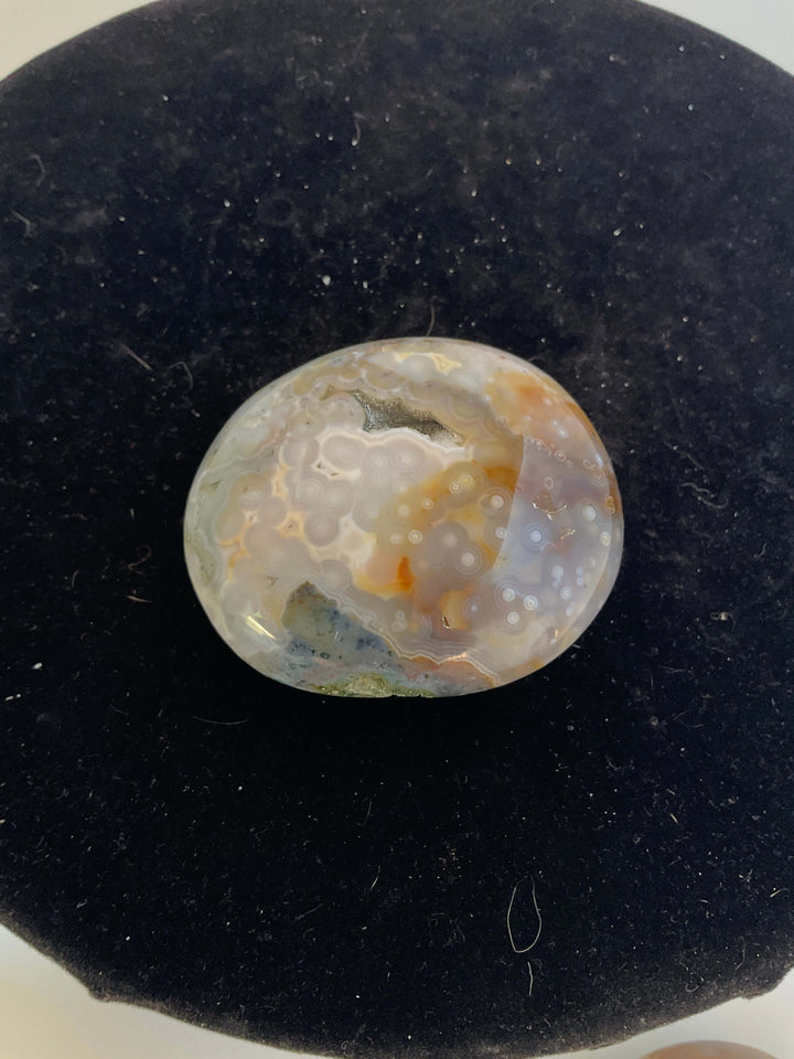 Ocean Jasper Pebble Palmstones displayed on a black background, showcasing its unique natural patterns.