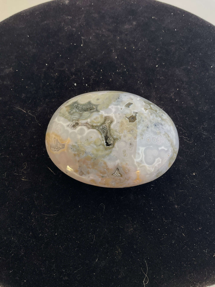 Ocean Jasper Pebble Palmstones displayed on a black background, showcasing its unique natural patterns.