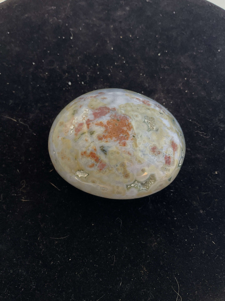 Ocean Jasper Pebble Palmstones displayed on a black background, showcasing its unique natural patterns.