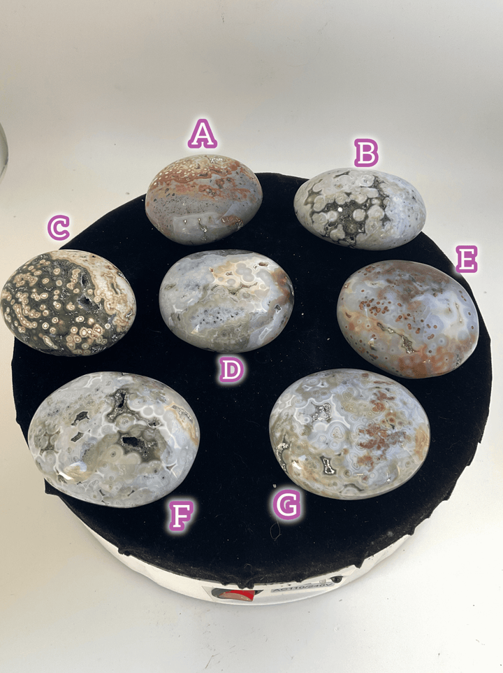 Ocean Jasper Pebble Palmstones displayed on a turntable, showcasing beautiful natural colors and textures.