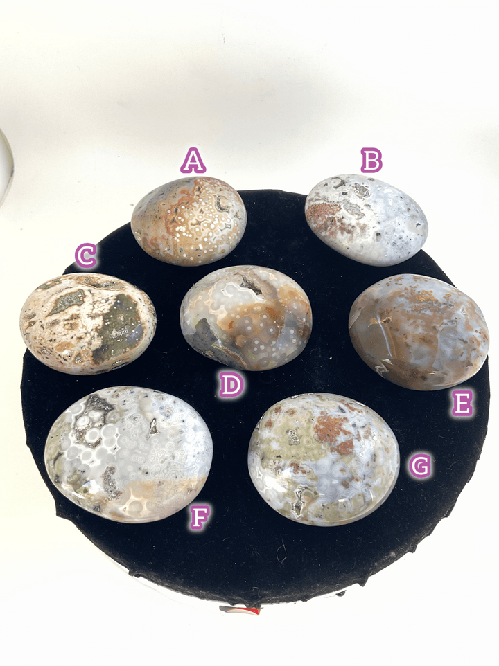 Ocean Jasper Pebble Palmstones displayed on a round black surface, showcasing natural beauty and unique designs.