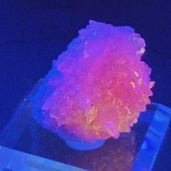 Vibrant Godzilla Calcite specimen from Guerrero, Mexico, displayed with UV light, showcasing beautiful colors.