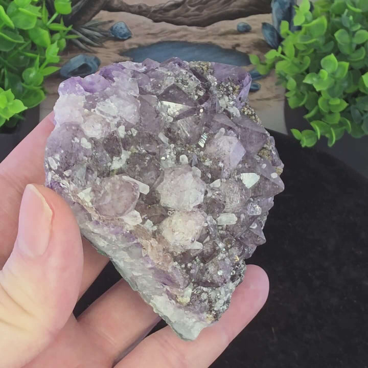 Embrace the raw beauty of nature with this unique Amethyst Geode Cluster. While it carries minor natural inclusions—perhaps hints of earthy hematite or other intriguing minerals—and some gentle signs of its journey, these features only add to its authenti
