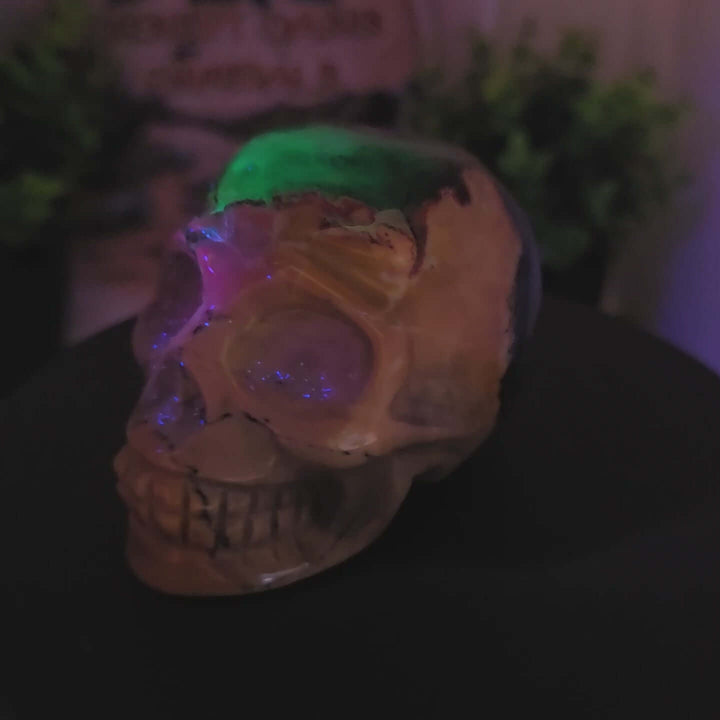 Volcano Agate Skull: Hand-Carved & UV Reactive Discover the captivating beauty of this hand-carved skull, crafted from natural Volcano Agate. This unique piece showcases the stone's inherent patterns, featuring striking bands of chalcedony and agate that