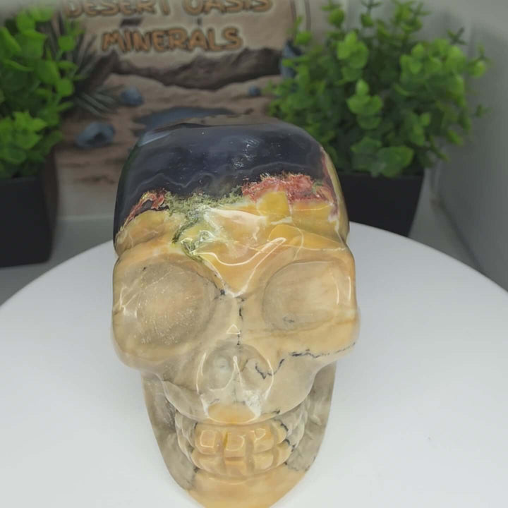 Volcano Agate Skull: Hand-Carved & UV Reactive Discover the captivating beauty of this hand-carved skull, crafted from natural Volcano Agate. This unique piece showcases the stone's inherent patterns, featuring striking bands of chalcedony and agate that