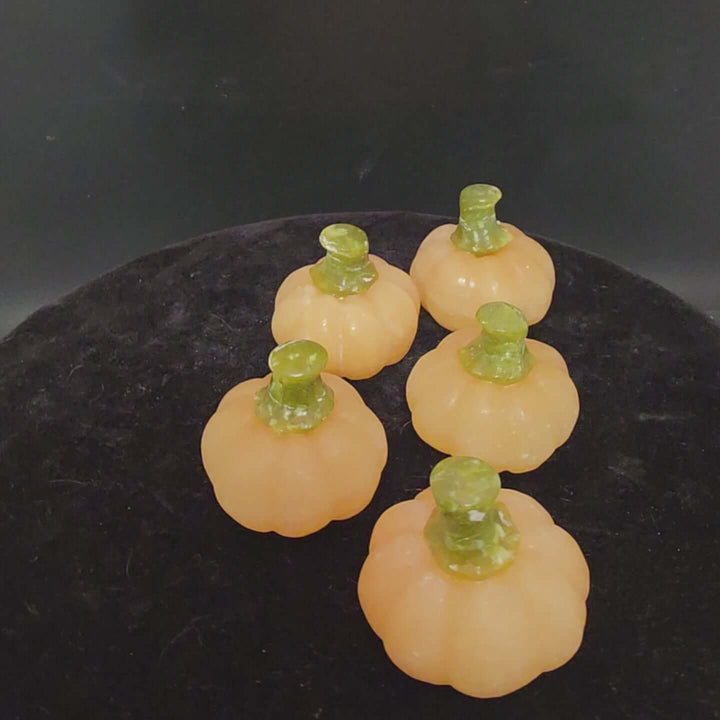 Five small orange calcite pumpkin carvings with green stems, perfect for display or decor.