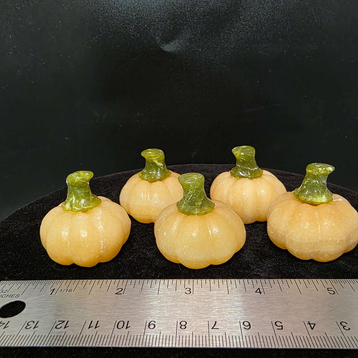 Five small orange calcite pumpkin carvings with green stems, perfect for display or decor.