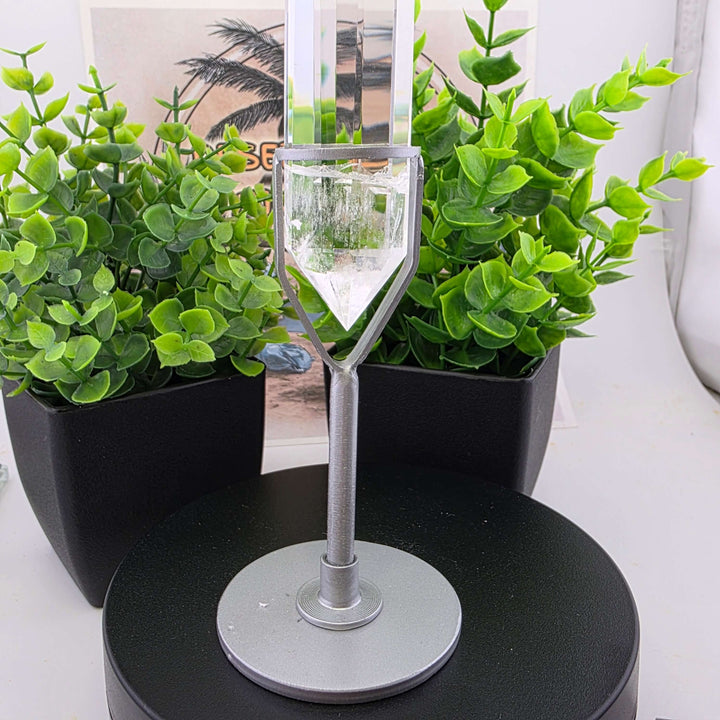 Polished Faceted Clear Quartz Crystal with Stand displayed among decorative plants.