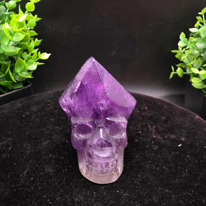 Amethyst Hand Carved Crystal Skull Wand Point Sculpture - 2.5 Inch displayed with two carved skulls and crystal points.