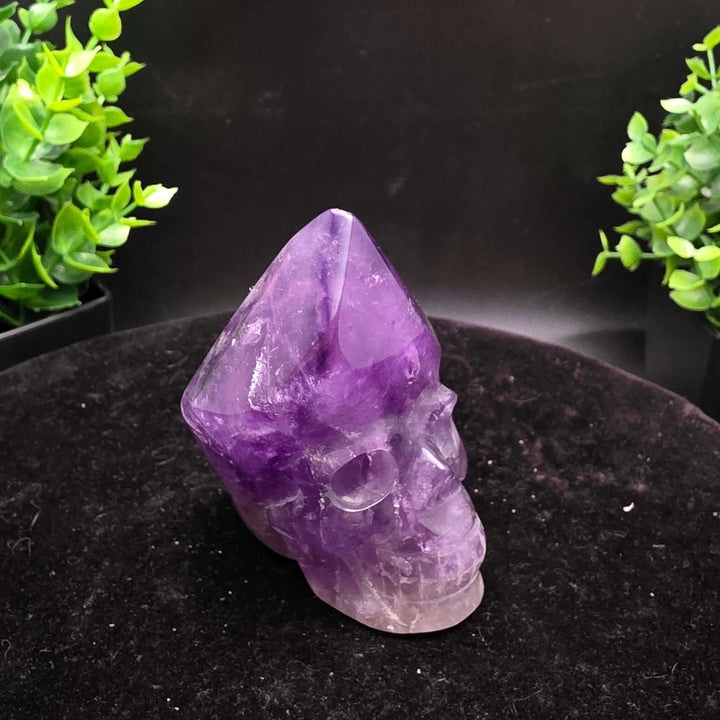 Amethyst Hand Carved Crystal Skull Wand Point Sculpture - 2.5 Inch displayed with two carved skulls and crystal points.