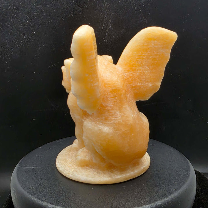 Yellow calcite gargoyle carving with wings relaxed, showcasing warm buttery yellow to honey-orange color.