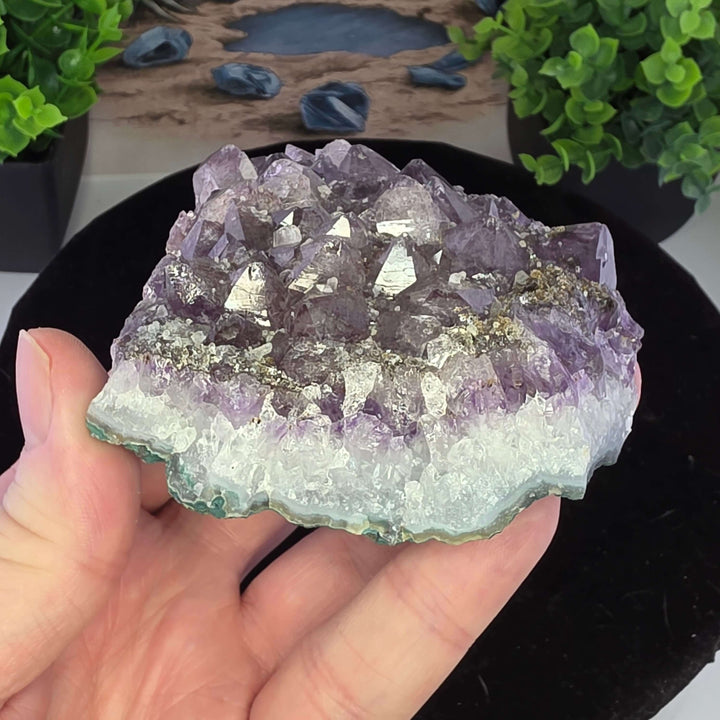 Embrace the raw beauty of nature with this unique Amethyst Geode Cluster. While it carries minor natural inclusions—perhaps hints of earthy hematite or other intriguing minerals—and some gentle signs of its journey, these features only add to its authenti