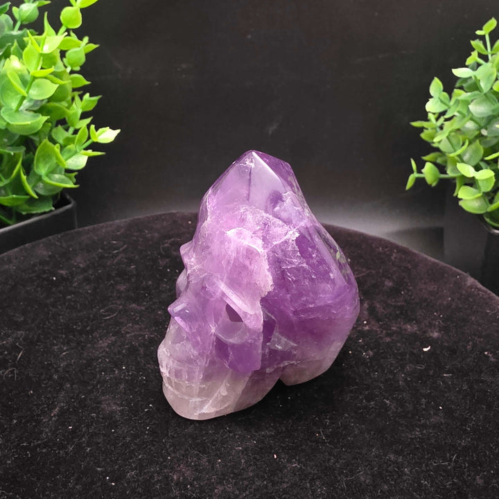 Amethyst Hand Carved Crystal Skull Wand Point Sculpture - 2.5 Inch displayed with two carved skulls and crystal points.