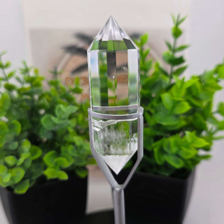  Polished Faceted Clear Quartz Crystal with Stand displayed among decorative plants.