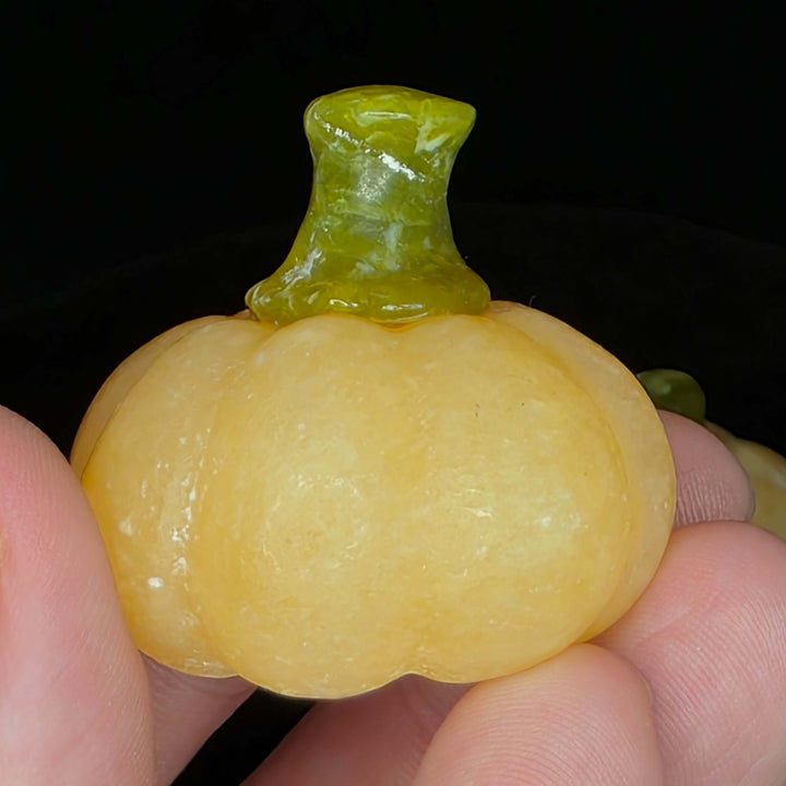 Small orange calcite pumpkin carving with a green stem, perfect for displays and decor.