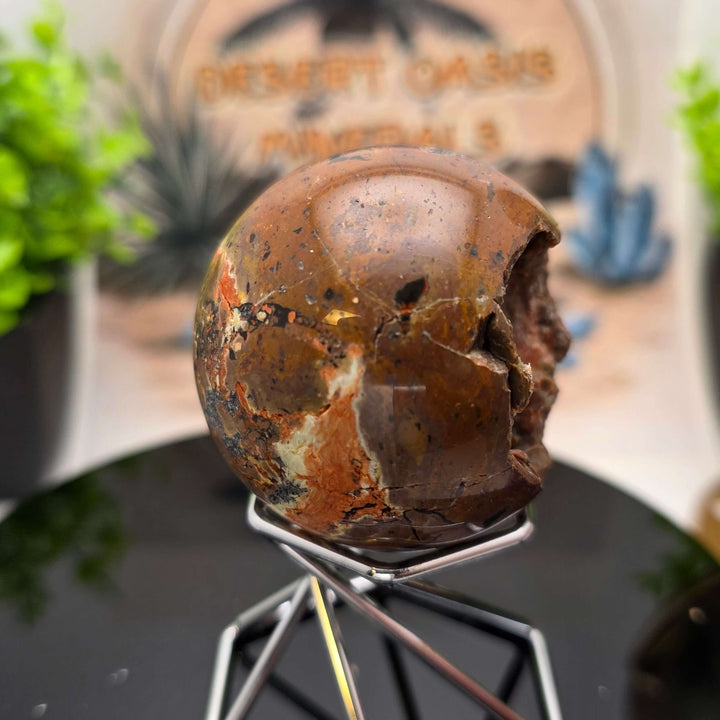 Red Fox Agate Sphere displayed in a stand, showcasing its shiny surface and unique cavities.