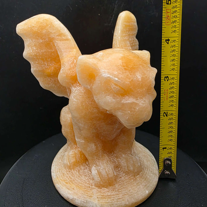 Yellow calcite gargoyle carving with wings relaxed, showcasing warm buttery yellow to honey-orange color.