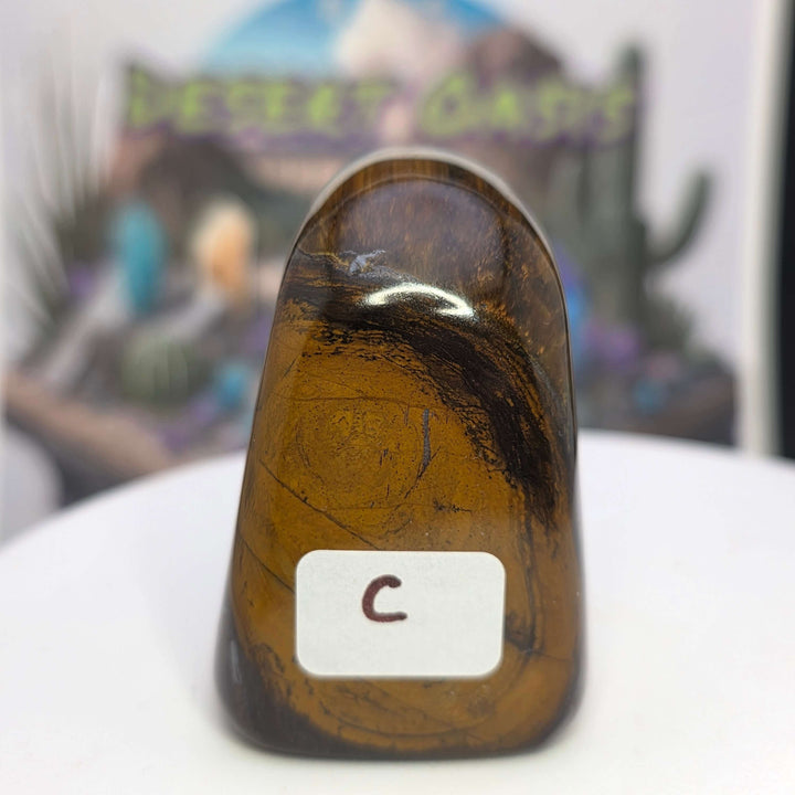 Polished Tiger's Eye freeform stone with golden hues and chatoyancy effect, showcasing its smooth surface and shimmering bands.