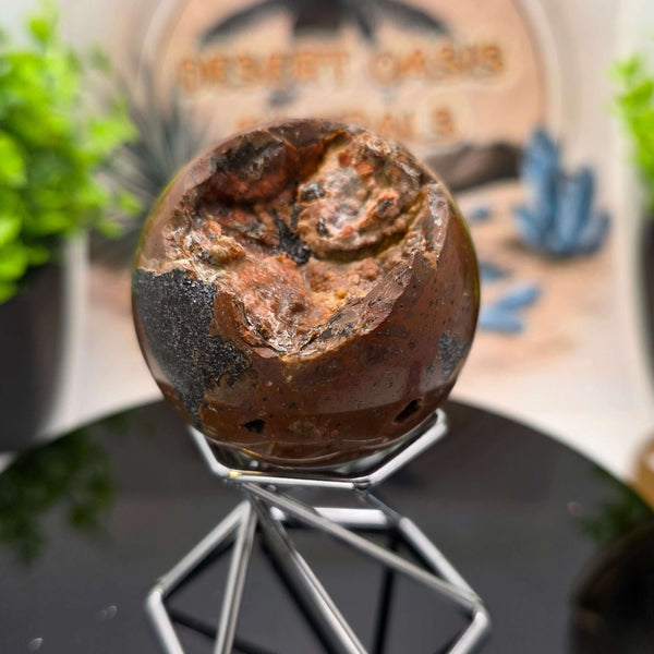 Red Fox Agate Sphere displayed in a stand, showcasing its shiny surface and unique cavities.