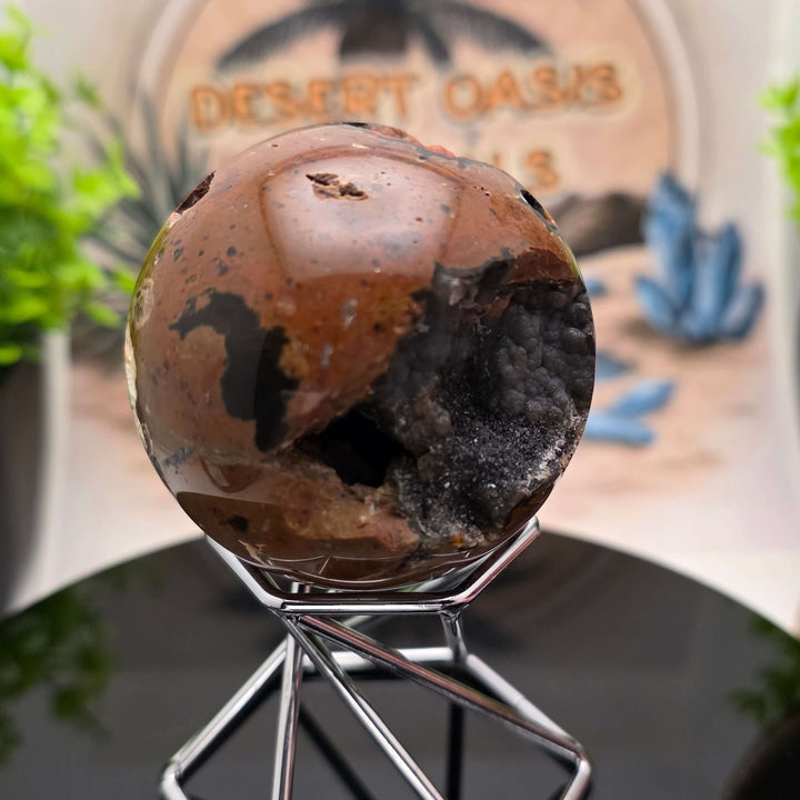 Red Fox Agate Sphere displayed in a stand, showcasing its shiny surface and unique cavities.