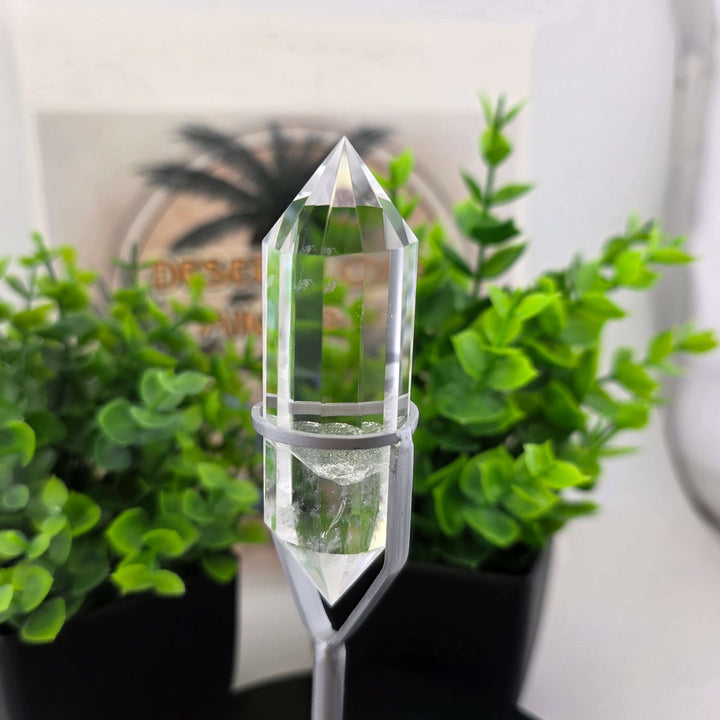  Polished Faceted Clear Quartz Crystal with Stand displayed among decorative plants.