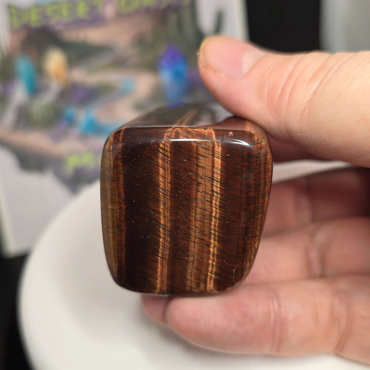 Polished Red Tiger's Eye freeform showing distinct reddish-brown colors held in hand, highlighting natural mineral effects.