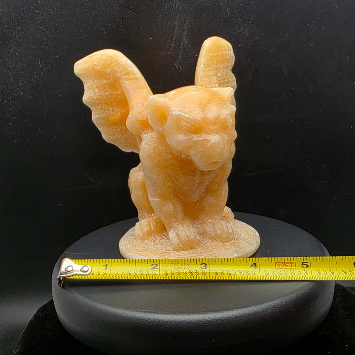 Yellow calcite gargoyle carving with wings relaxed, showcasing warm buttery yellow to honey-orange color.