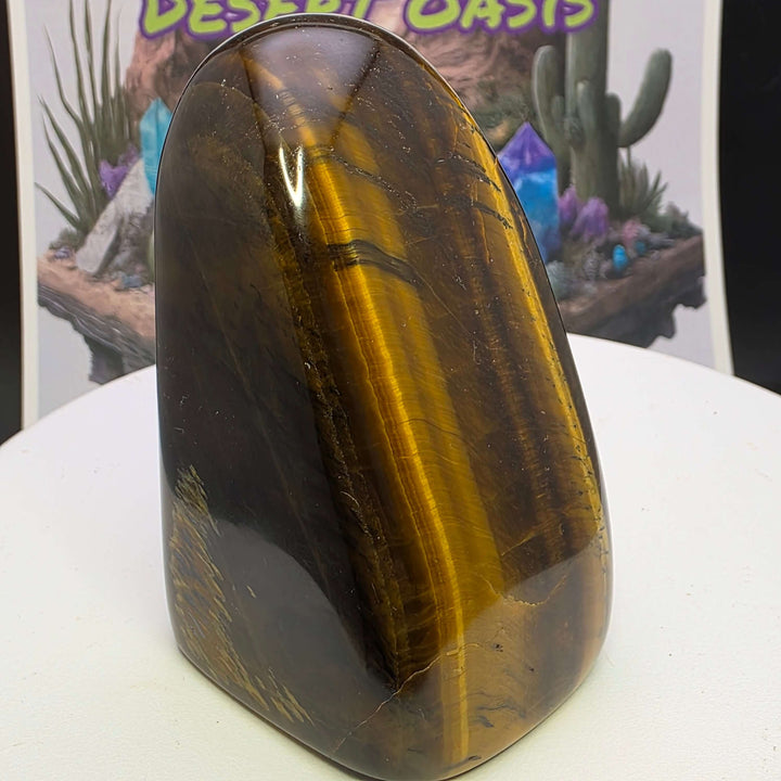 Polished Tiger's Eye freeform displaying golden chatoyancy and smooth texture on a white pedestal.