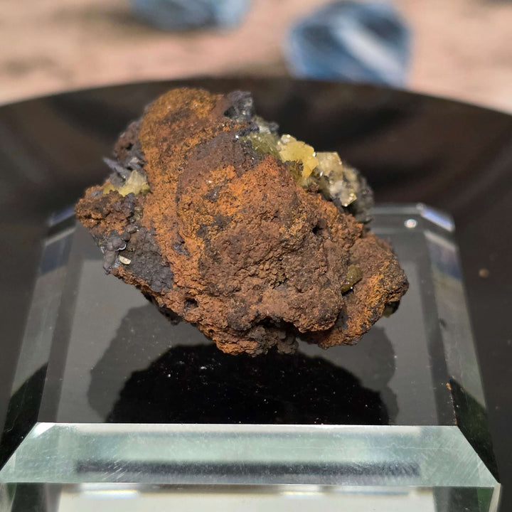 Adamite Specimen from Ojuéla Mine displayed on a glass stand, showcasing its unique crystal formation and colors.