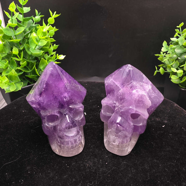 Amethyst Hand Carved Crystal Skull Wand Point Sculpture - 2.5 Inch displayed with two carved skulls and crystal points.