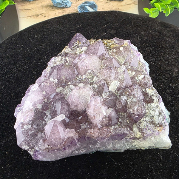 Embrace the raw beauty of nature with this unique Amethyst Geode Cluster. While it carries minor natural inclusions—perhaps hints of earthy hematite or other intriguing minerals—and some gentle signs of its journey, these features only add to its authenti