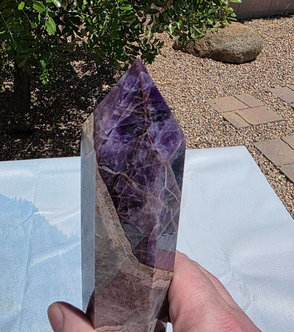 Beautiful chevron amethyst tower with deep purple colors, excellent point, and steady base. Picture taken on sunlight to show the beautiful colors. Over a foot tall with beaitiful polish Chevron amethyst, also known as banded amethyst or dream amethyst, i