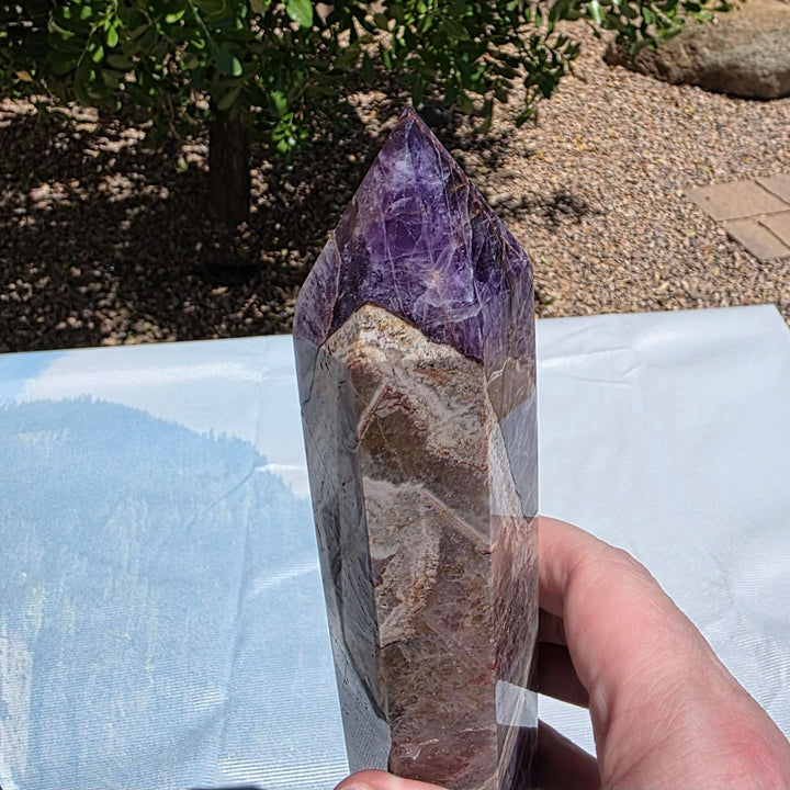 Beautiful chevron amethyst tower with deep purple colors, excellent point, and steady base. Picture taken on sunlight to show the beautiful colors. Over a foot tall with beaitiful polish Chevron amethyst, also known as banded amethyst or dream amethyst, i