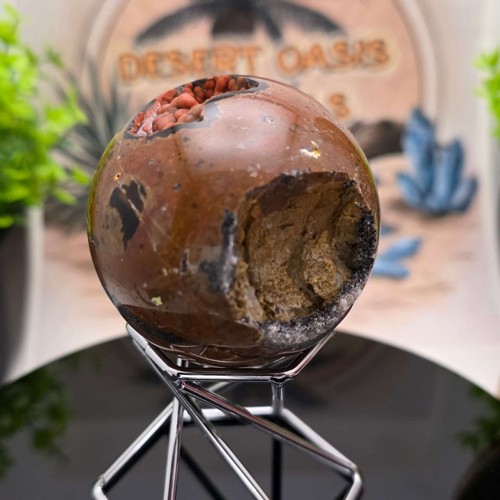 Red Fox Agate Sphere displayed in a stand, showcasing its shiny surface and unique cavities.