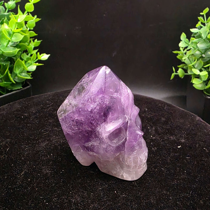 Amethyst Hand Carved Crystal Skull Wand Point Sculpture - 2.5 Inch displayed with two carved skulls and crystal points.