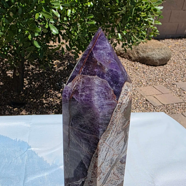 Beautiful chevron amethyst tower with deep purple colors, excellent point, and steady base. Picture taken on sunlight to show the beautiful colors. Over a foot tall with beaitiful polish Chevron amethyst, also known as banded amethyst or dream amethyst, i