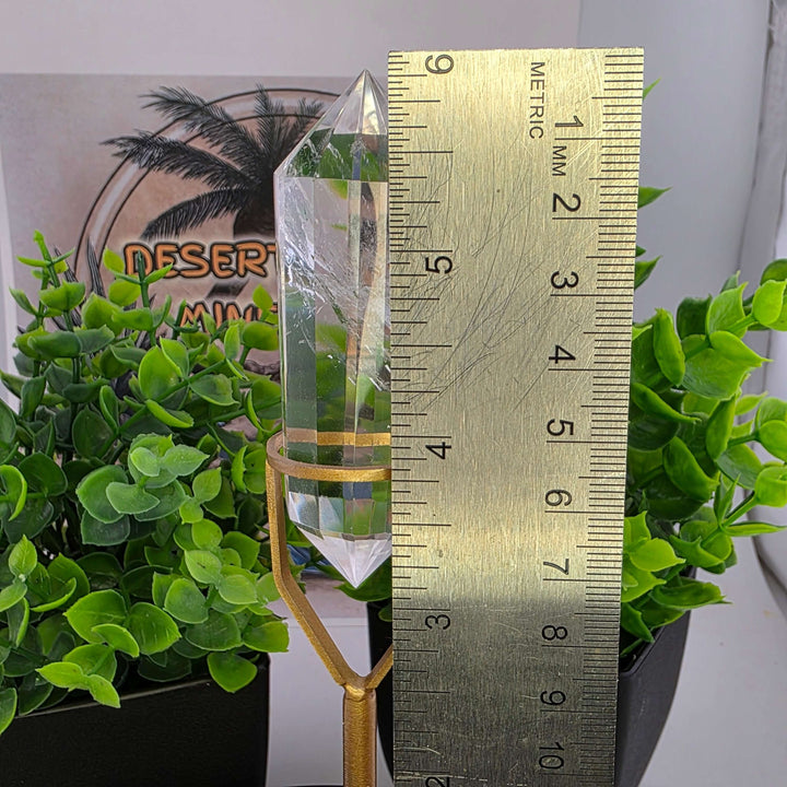 Polished Faceted Clear Quartz Crystal with Stand displayed among greenery.